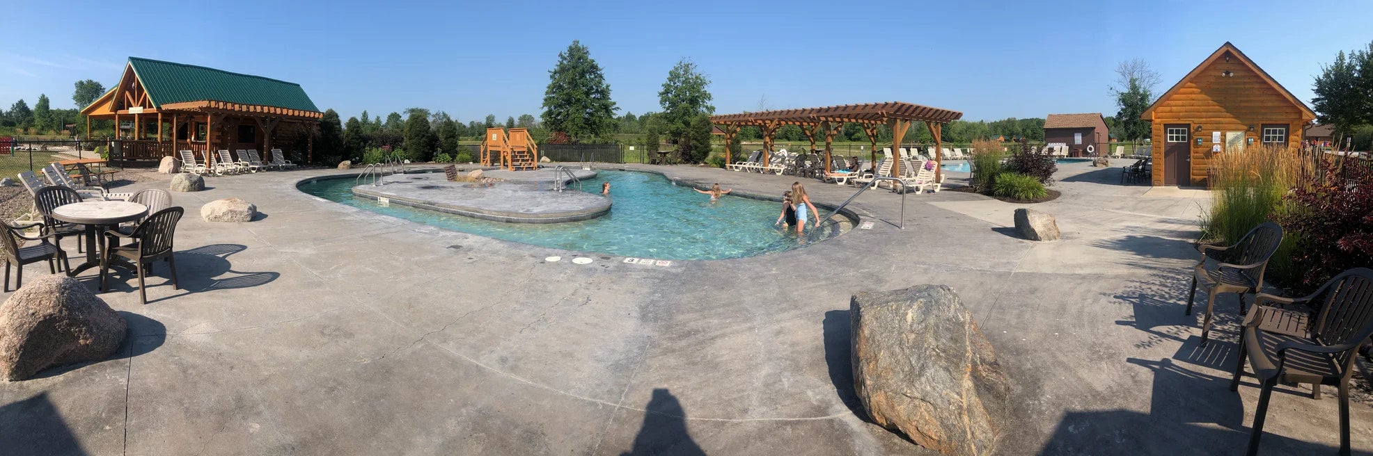 Lagoon pool surrounded by cabins and lawn chairs at Branches of Niagara Campground.