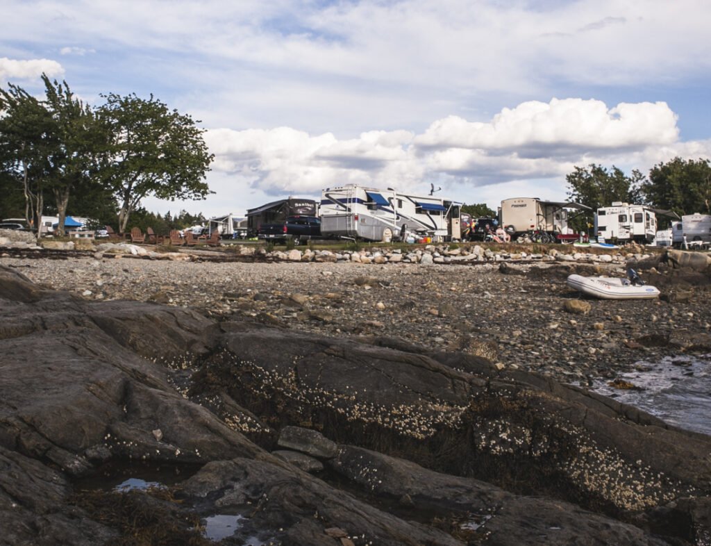 Rocky shoreline in the foreground with RVs in the distance
