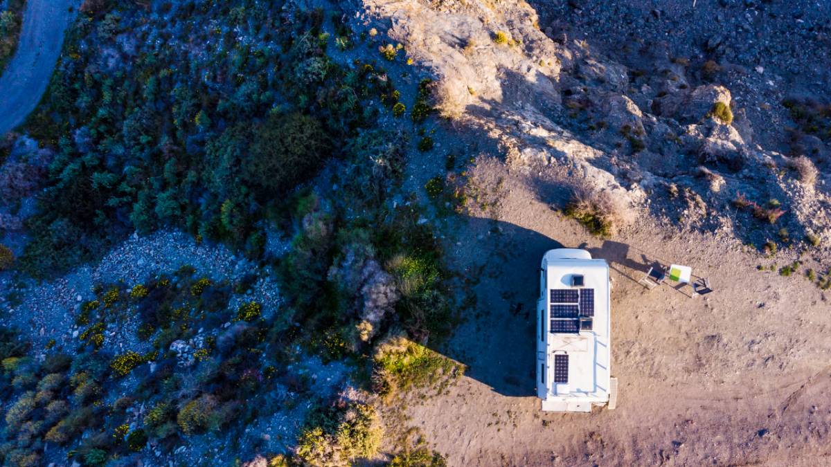 RV with solar panels on roof camping on cliff sea shore. with shadows to the driver's side