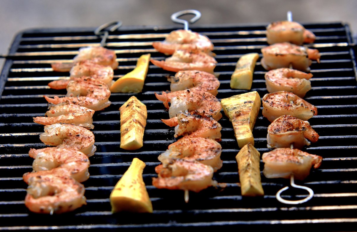 Shrimp skewers cooking on grill with vegetables