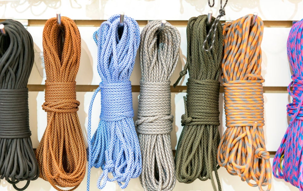 seven bundles of paracord strung up on racks in a store.