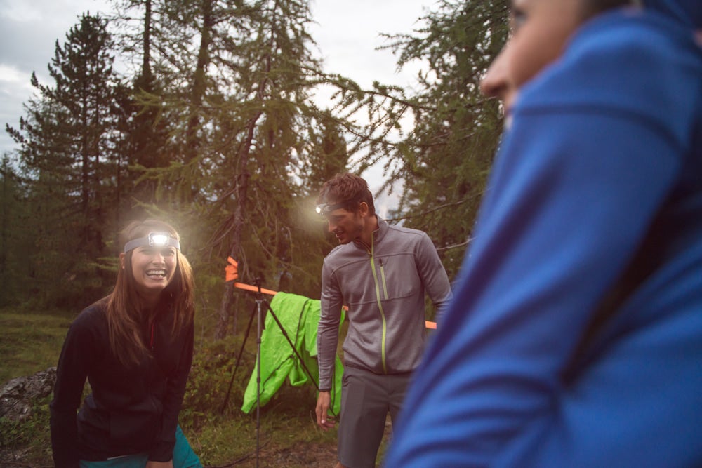 three campers wearing headlamps in the outdoors at dusk