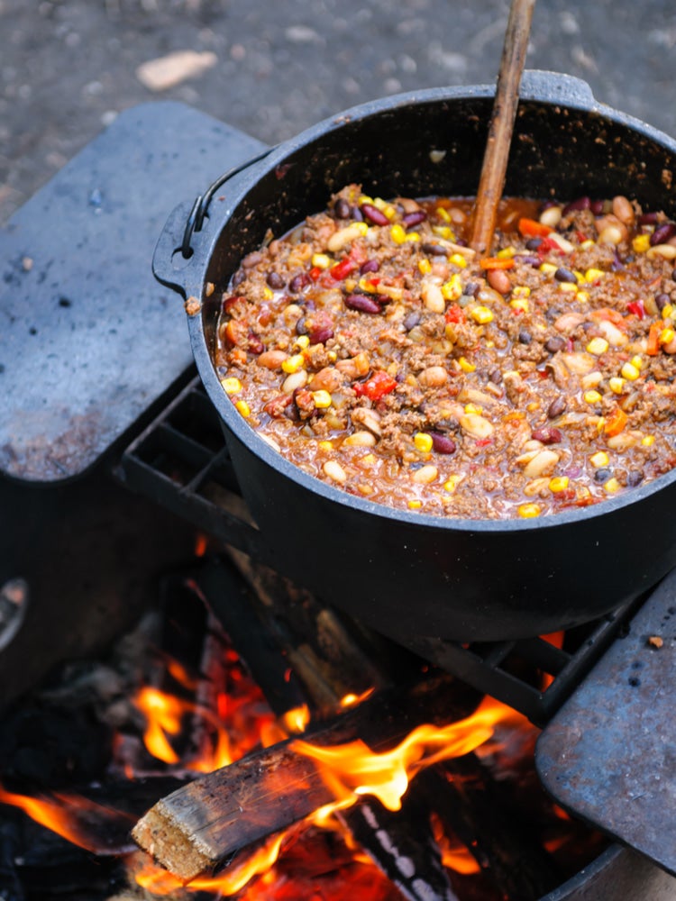 a pot of chili over a campfire