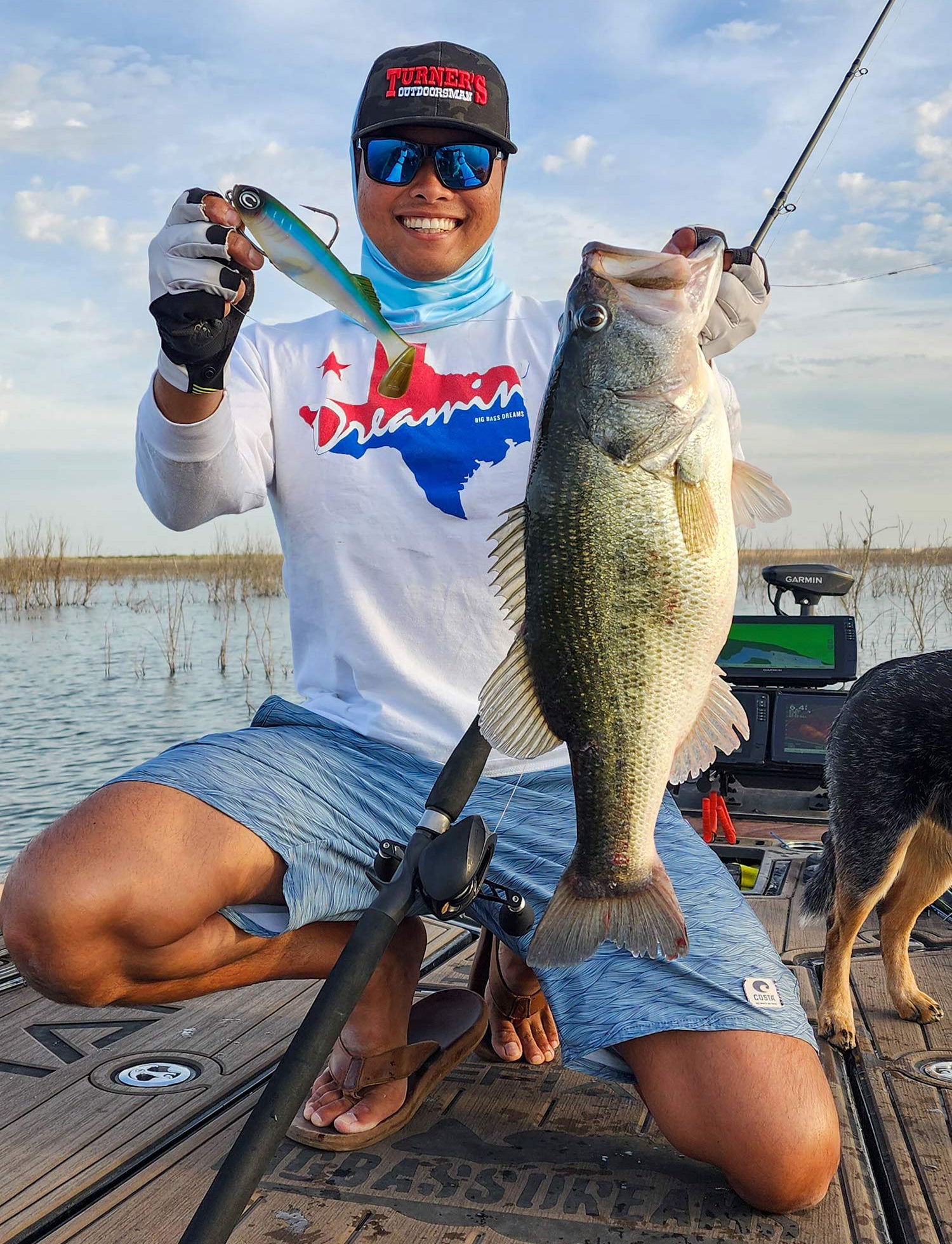 smiling angler holds up fishing lure and largemouth bass