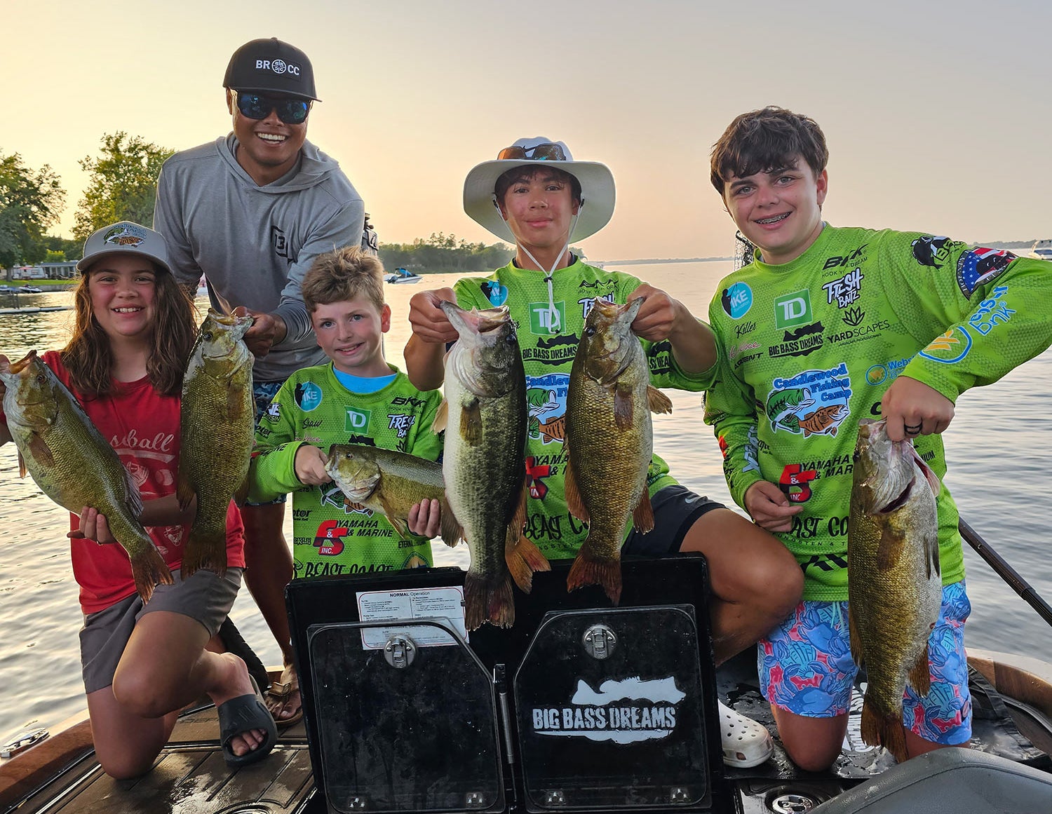 Angler Oliver Ngy poses with four young campers holding six largemouth bass.