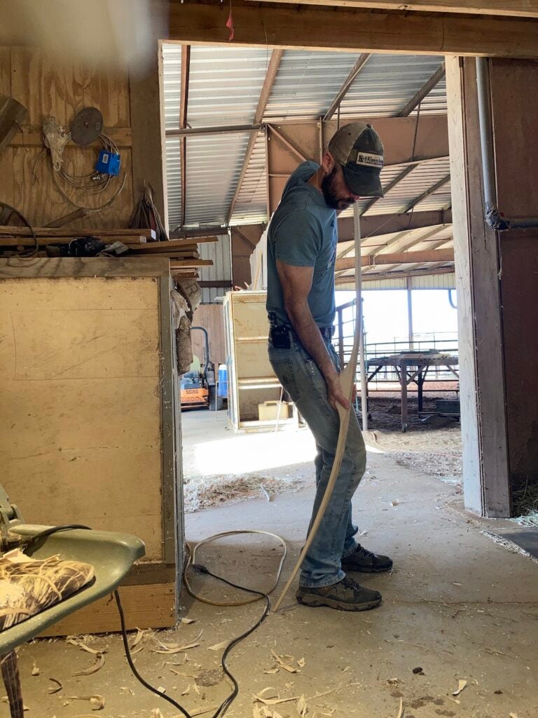 A man bending a wooden bow on the floor