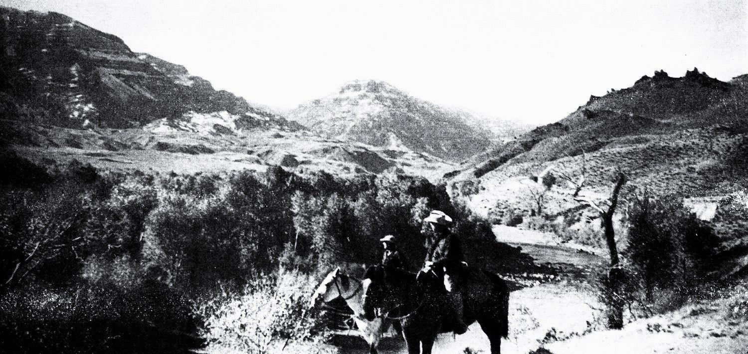 two hunters on horseback in mountainous country