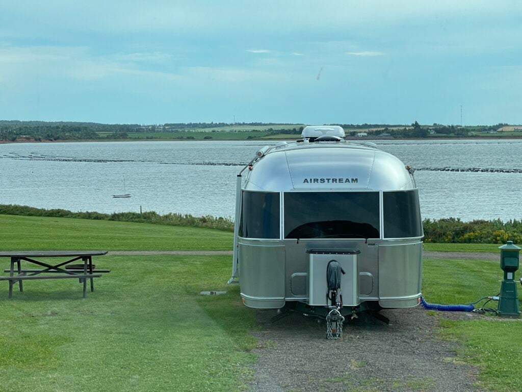 Airstream trailers are popular in the used RV market. Here one is set up in a campground with a view