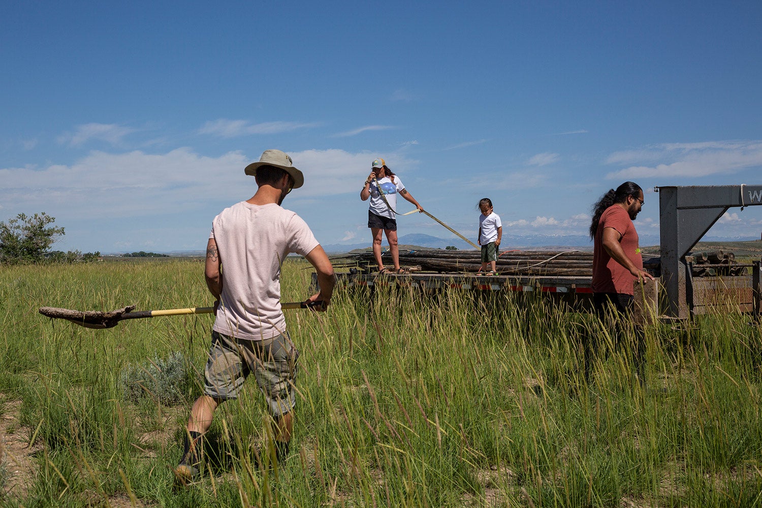 one person collects buffalo chips on prairie while others to fence repair