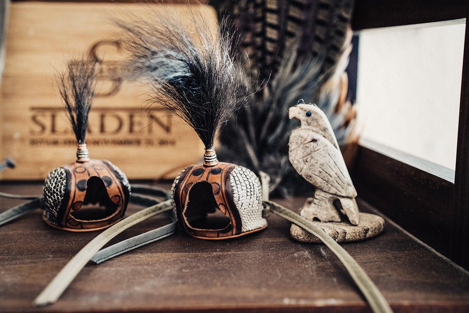 two falconry bird hoods and a wood carving of a hawk