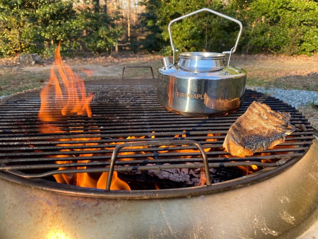 A kettle and piece of bread over the Solo Stove fire pit flame