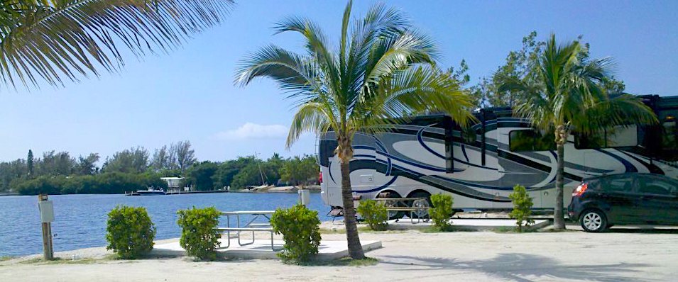 Large Class A parked under palm trees backed up to a lake in Florida