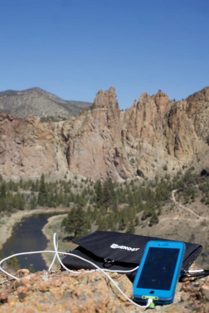 a cell phone plugged into a renogy charger perched on a rock cliff