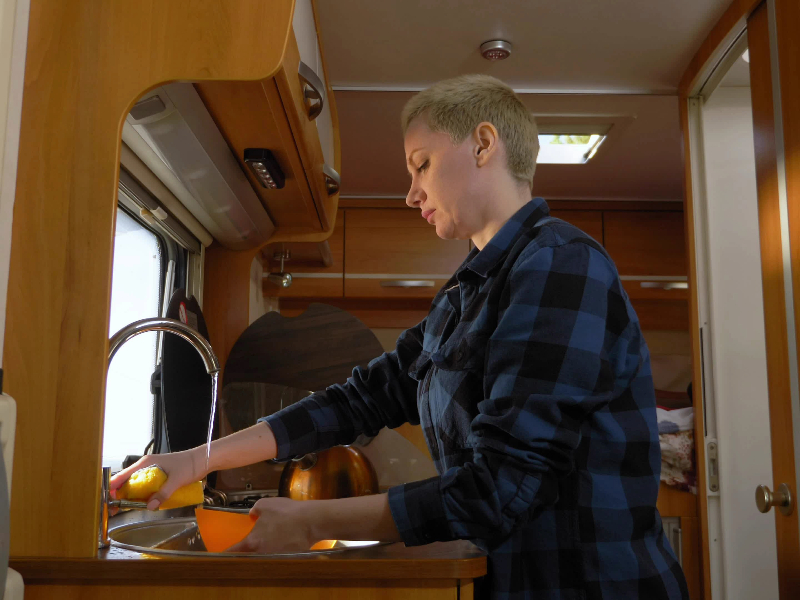 Woman washing dishes in an RV sink - green RVing