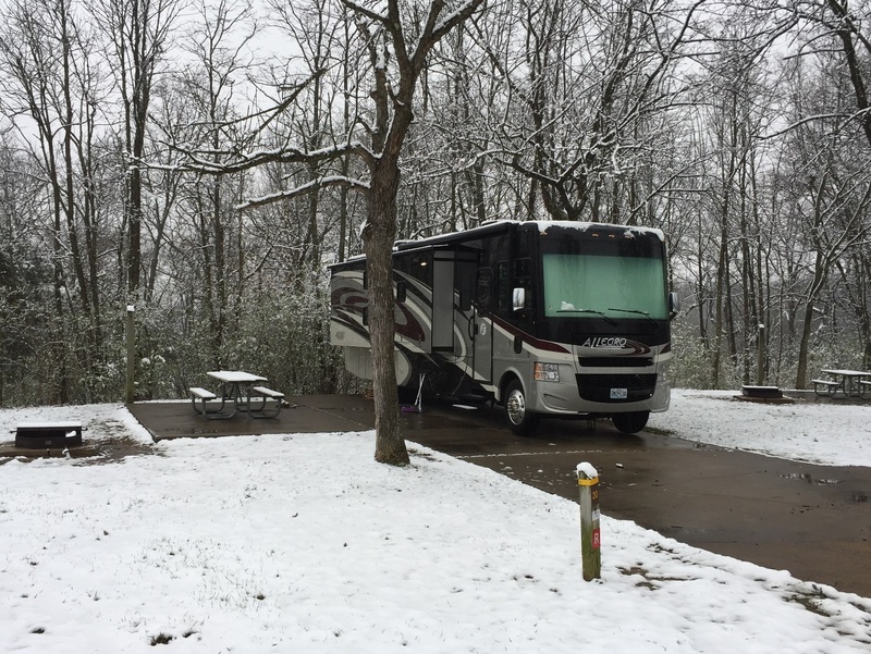 Class A RV parked in a ccampground with snow covered ground