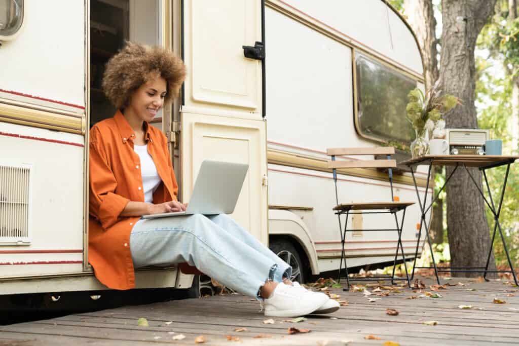 Woman uses laptop outside of RV via mobile internet.