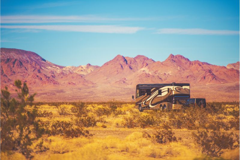 Class A motorhome towing a jeep through the desert