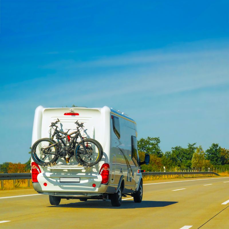 European RV with bikes on the back driving down the highway
