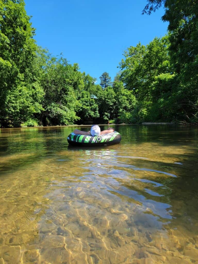 A man floating in an innertube down the Piney River.