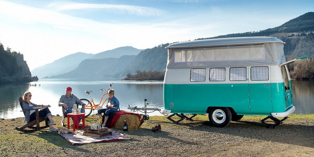 Family next to lake with turquoise vintage camper