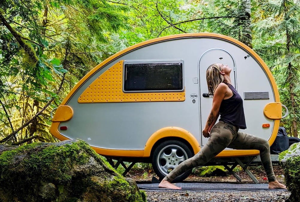 Woman doing yoga in front of yellow and gray trailer