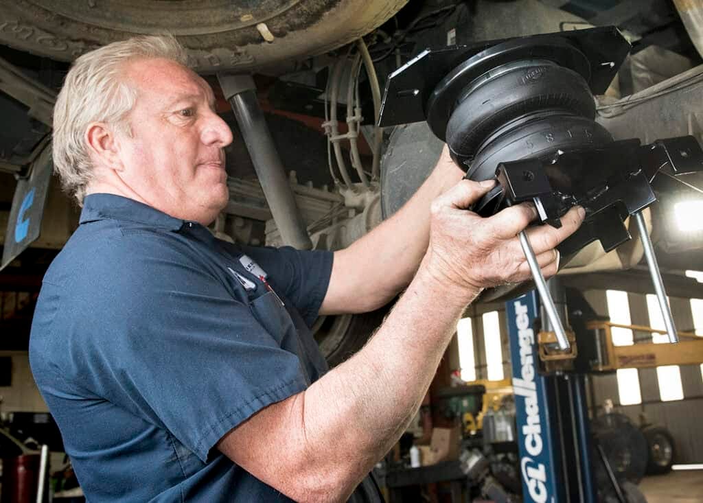 An RV tech installing air bags on a truck to improve the ride of a truck carrying a slide-in camper. Photo: Bruce W. Smith.