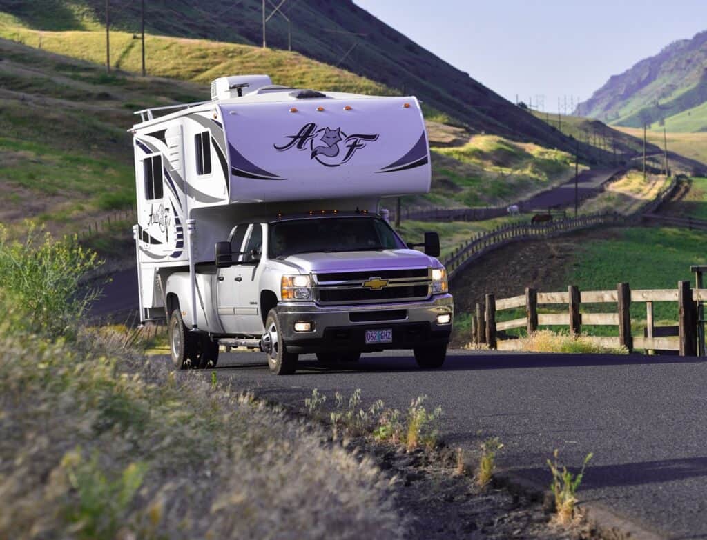 A truck with upgraded ride and handling due to the installation of a sway bar hauling a pickup camper on the road. Photo: Bruce Smith.