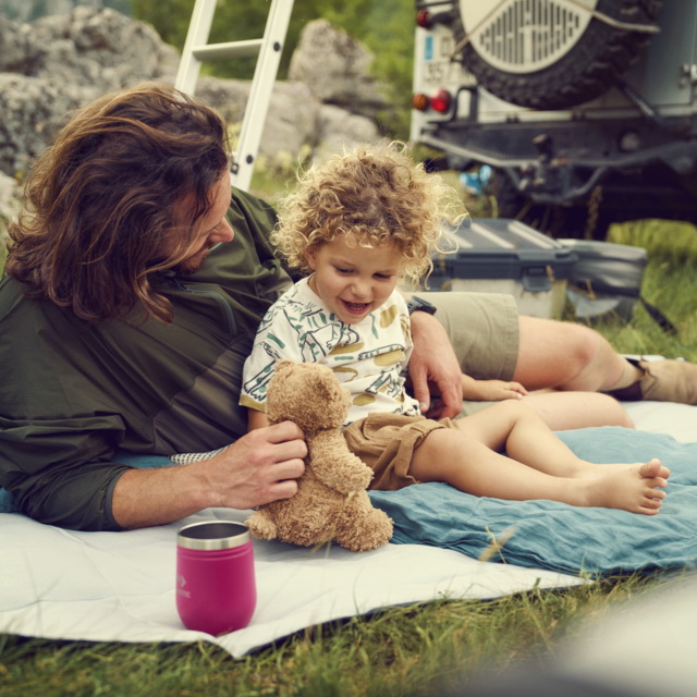 dad and toddler relaxing on a Dometic Camping Blanket.