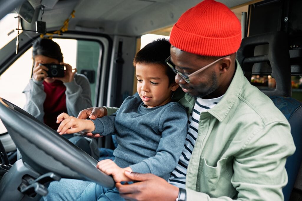 Child sitting on mans lap in drivers seat - RV travel with toddlers