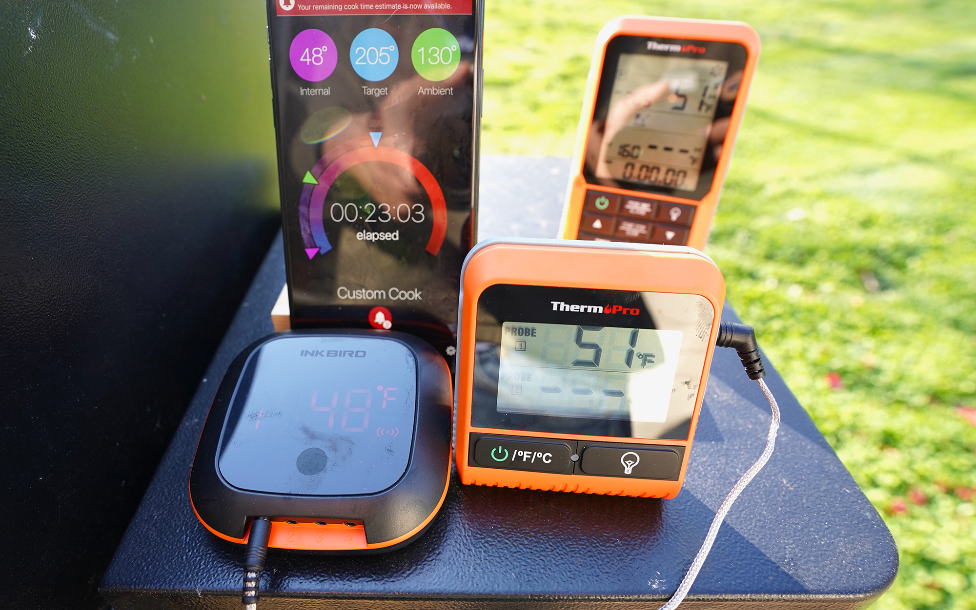 Three wireless meat thermometers sit on a BBQ.