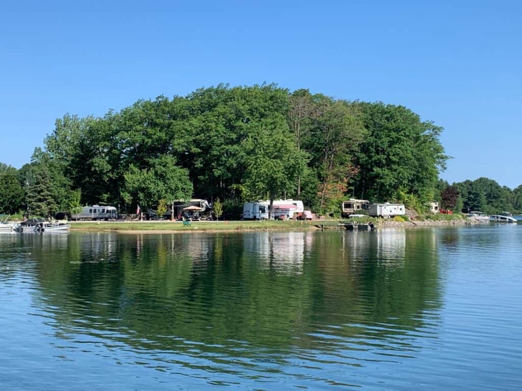 A photo of Holiday Park Campground's lakefront sites with RVs in them, taken from the water.