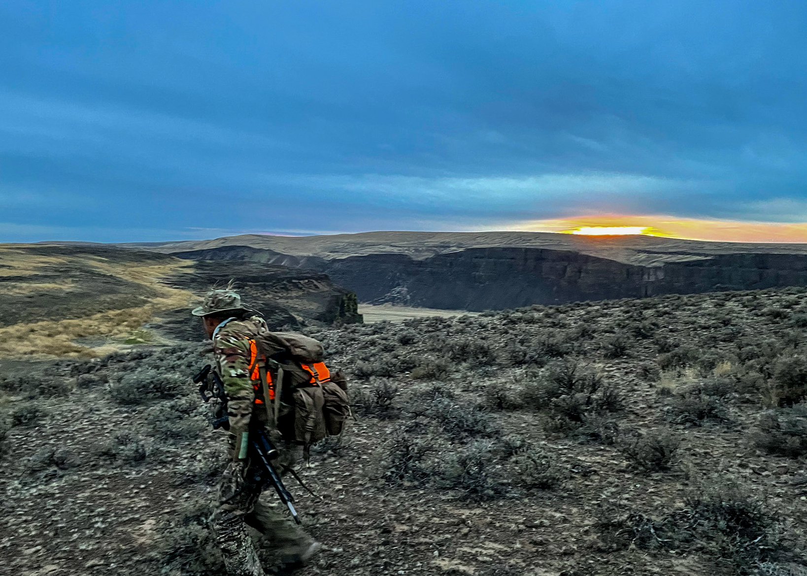 A hunter jogs along a hillside.