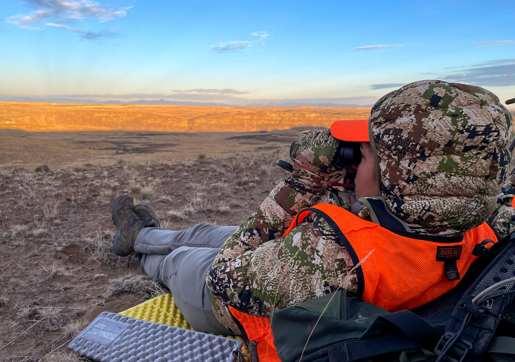 A hunter looks through binoculars.