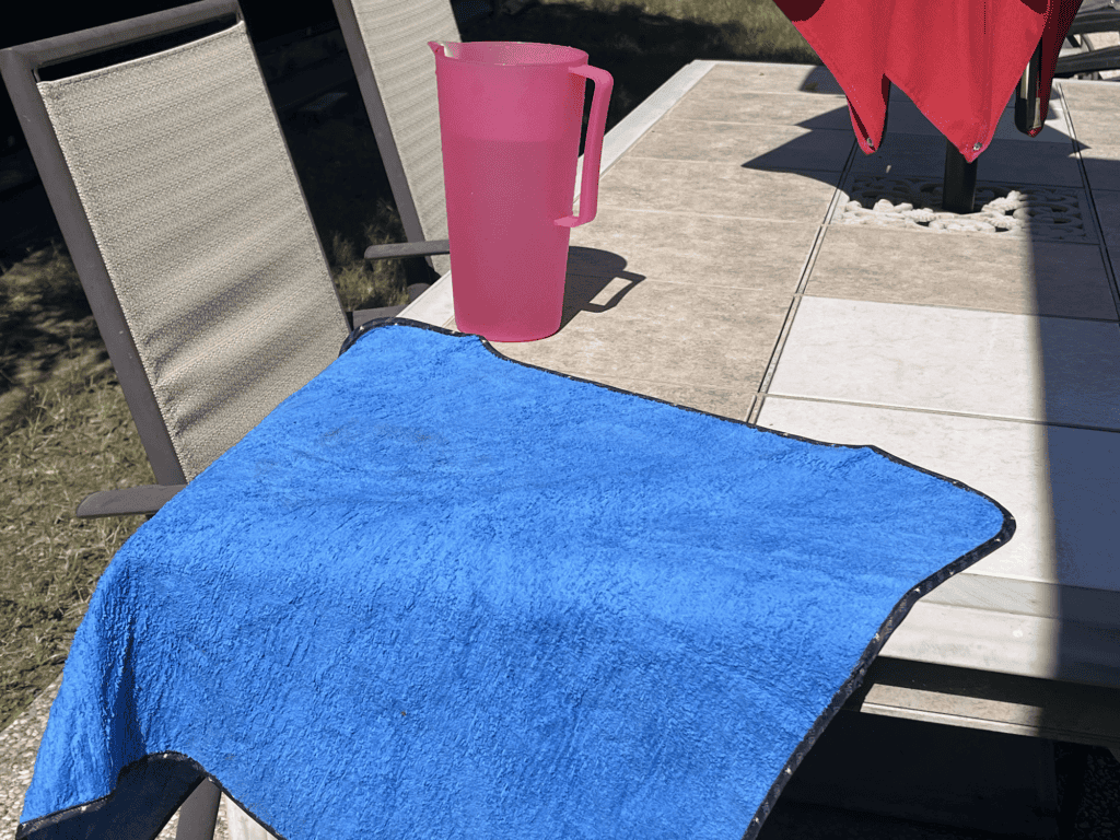 Drying towel and a 1/2 gallon pitcher on an outdoor table.
