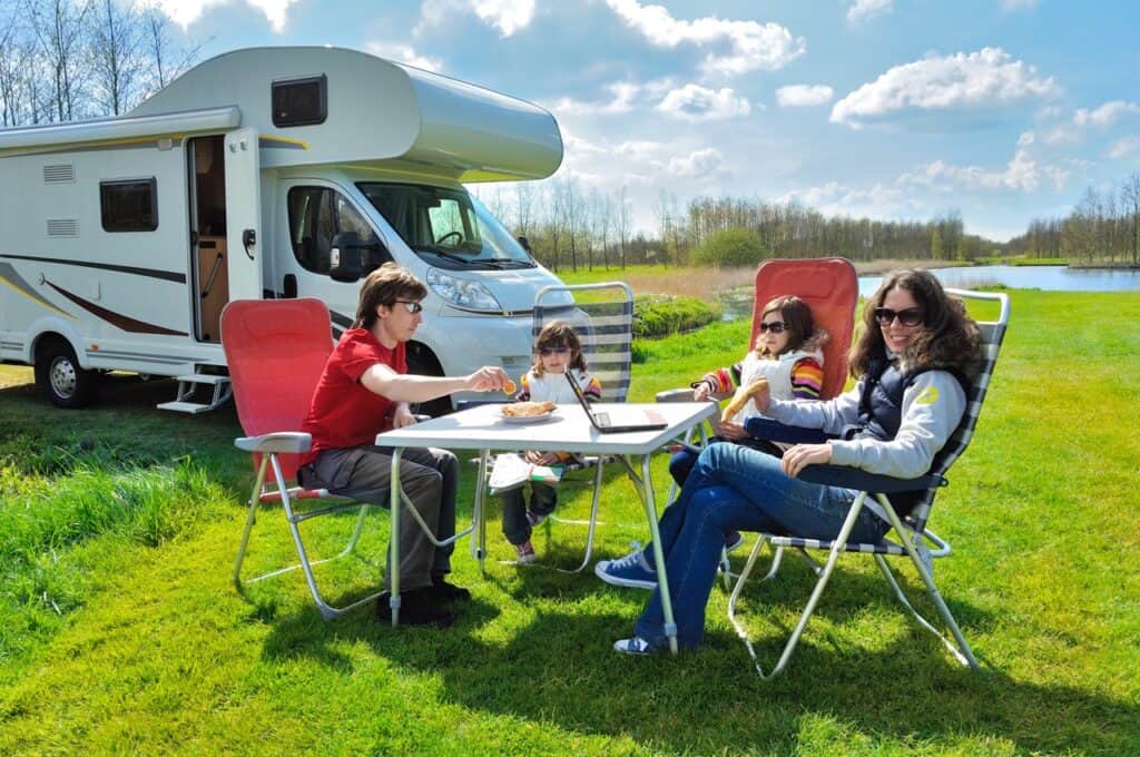 A family eating at a table in front of their RV at an RV site. Photo: Shutterstock.