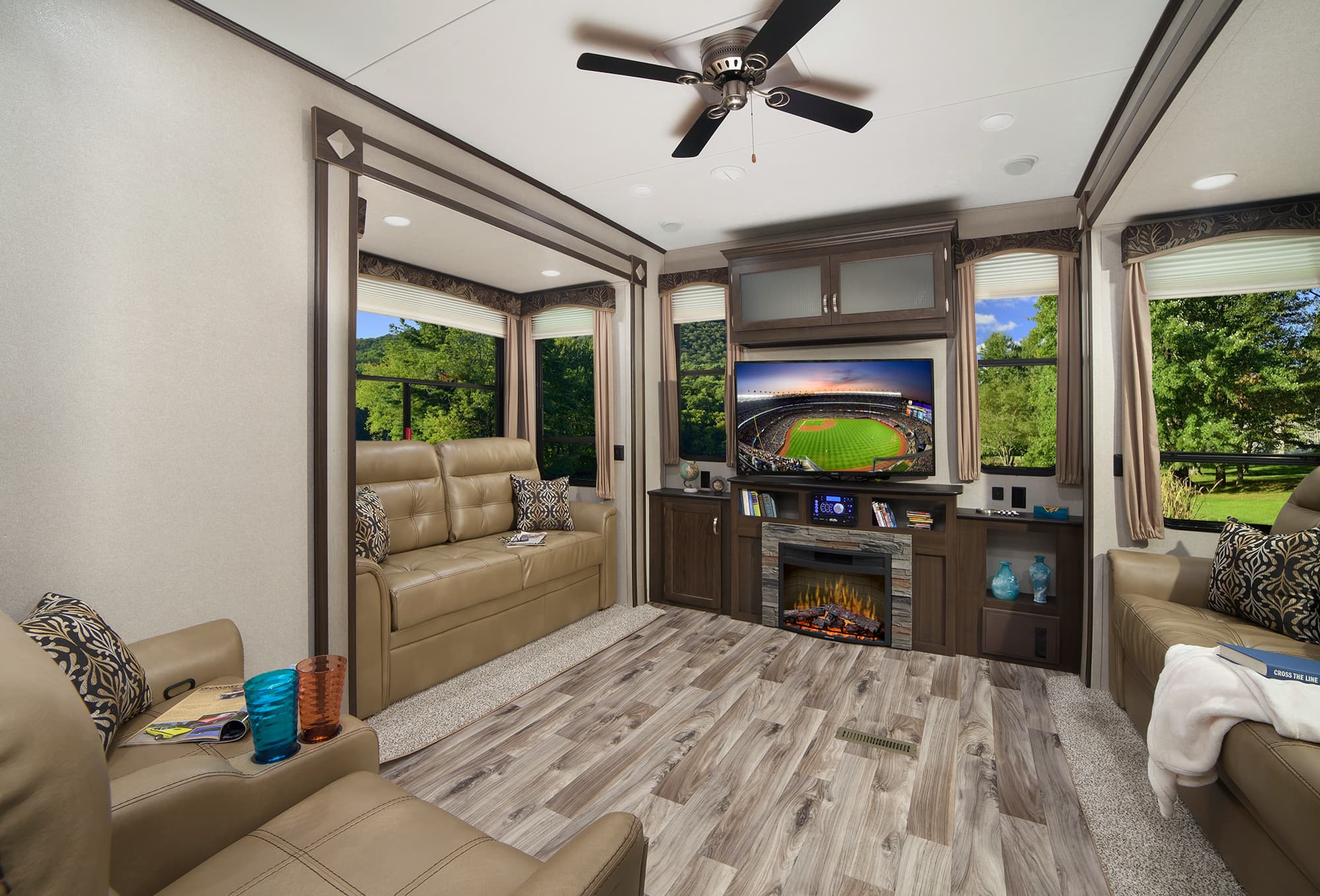 interior of a destination trailer with couches wood floor fireplace and tv