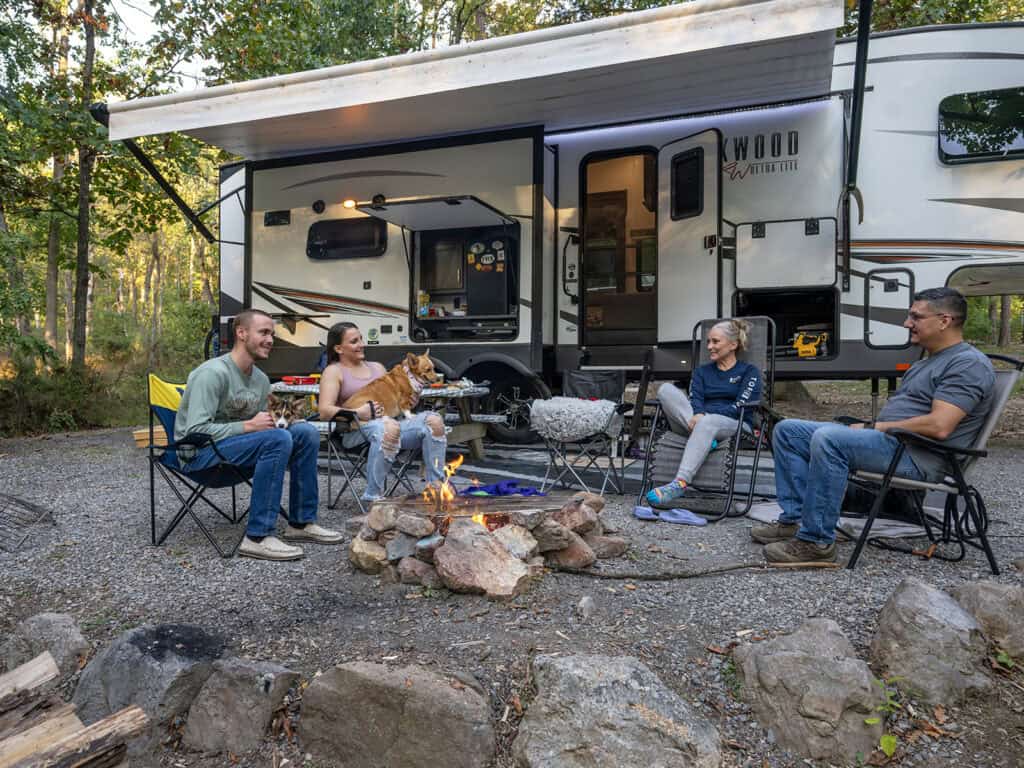 RVers and a dog enjoy campfire time outside of their 5th wheel at Endless Caverns