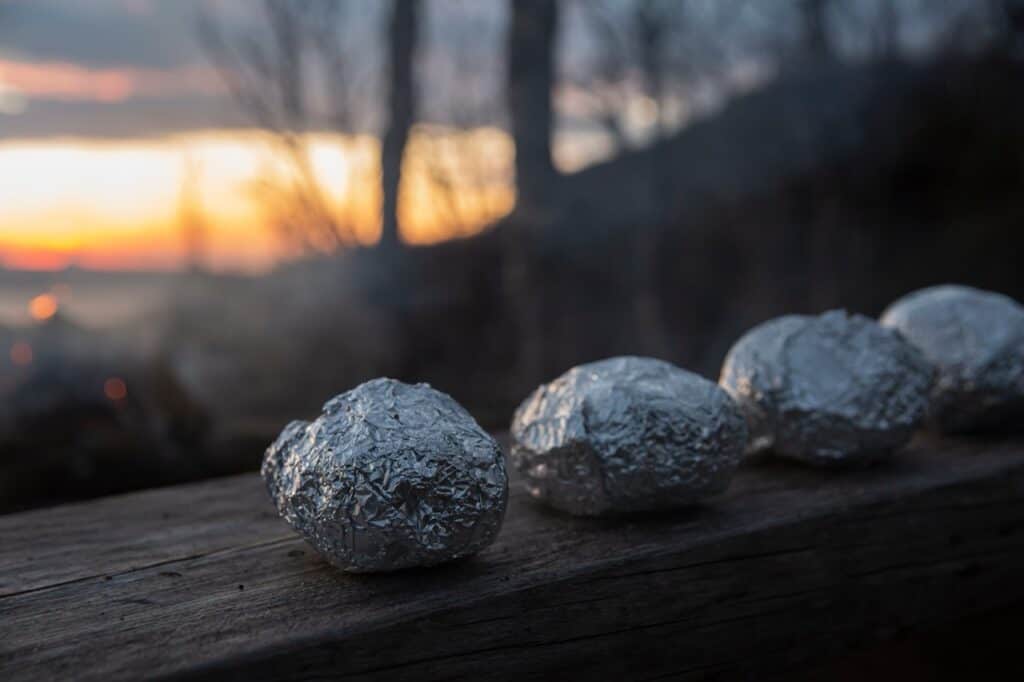 Four muffins wrapped in aluminum foil.