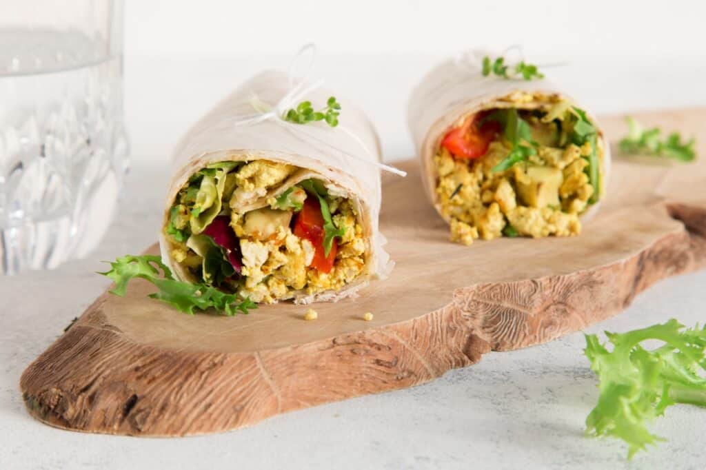 A Tofu scramble wrap on a wooden tray.