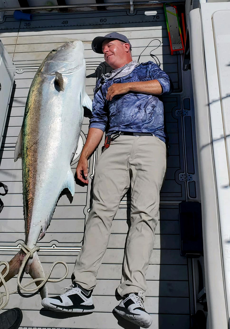 Angler lies next to huge amberjack.