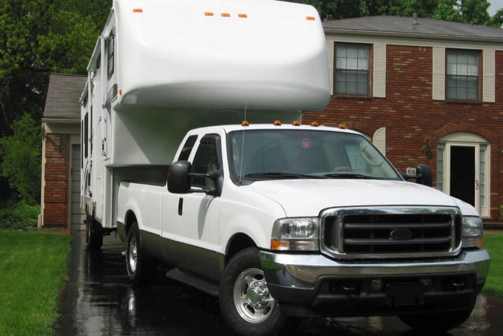 5th-wheel RV backed into a driveway with full-size truck