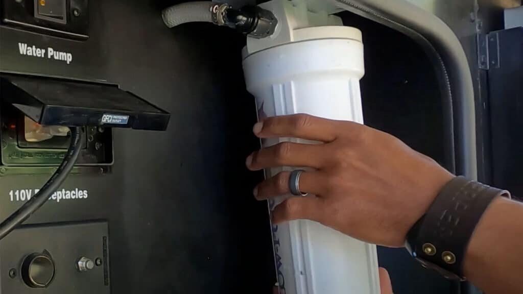 Person attaching a water filter to an RV