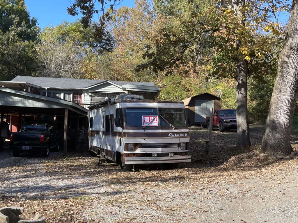 an old moroehome in a driveway with a For Sale sign in the window