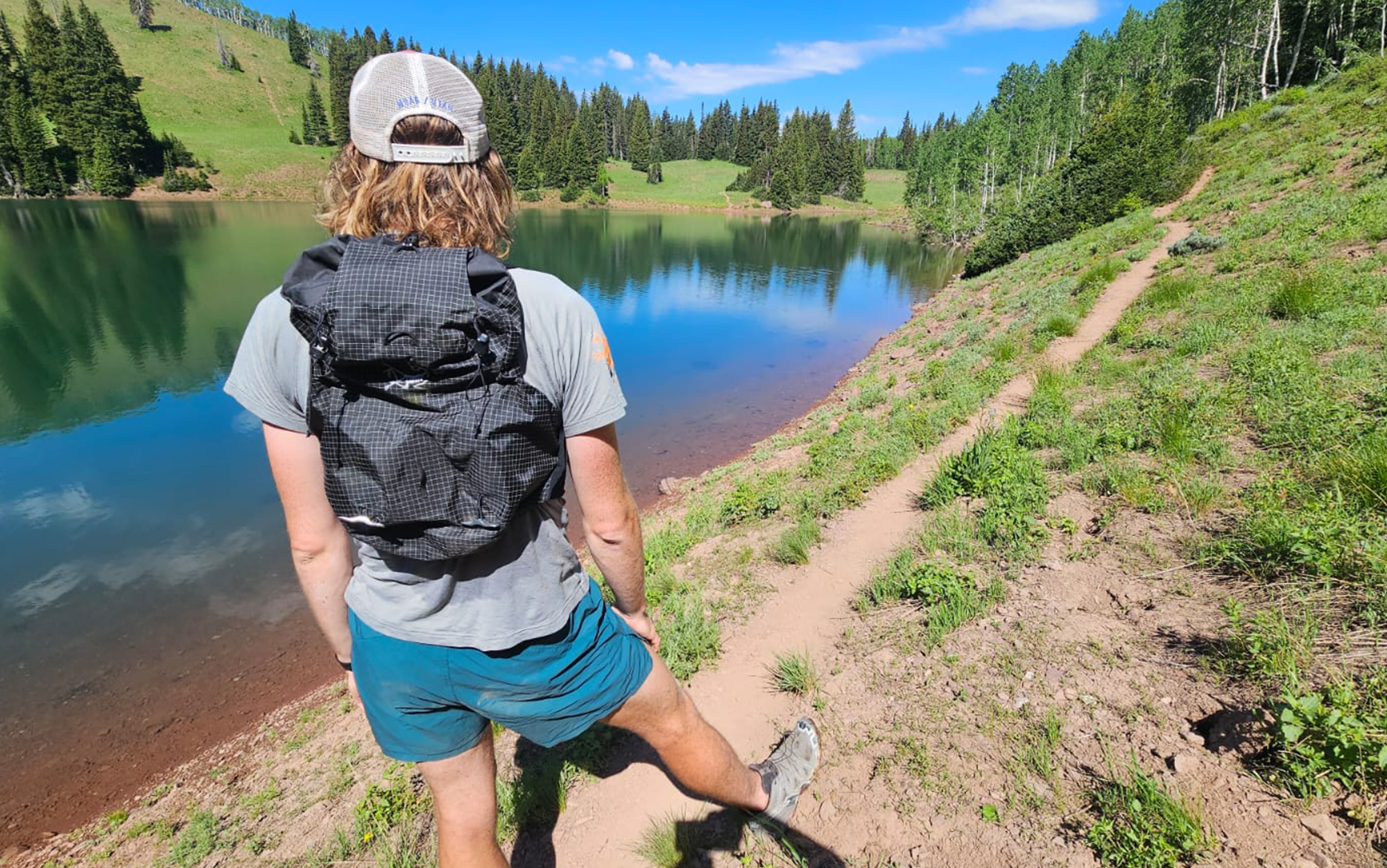 Runner wears Norvan running vest near alpine lake.