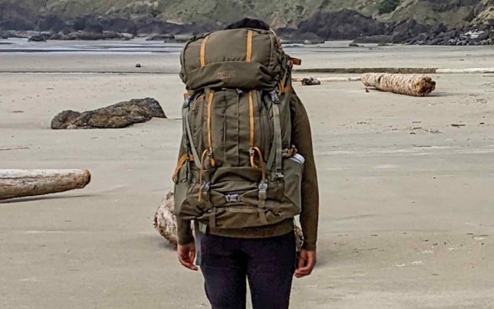  Woman walking across beach wearing the Mystery Ranch Bridger