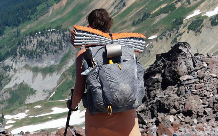  woman walking down a mountain ridge wearing the REI Flash Air 50 backpack