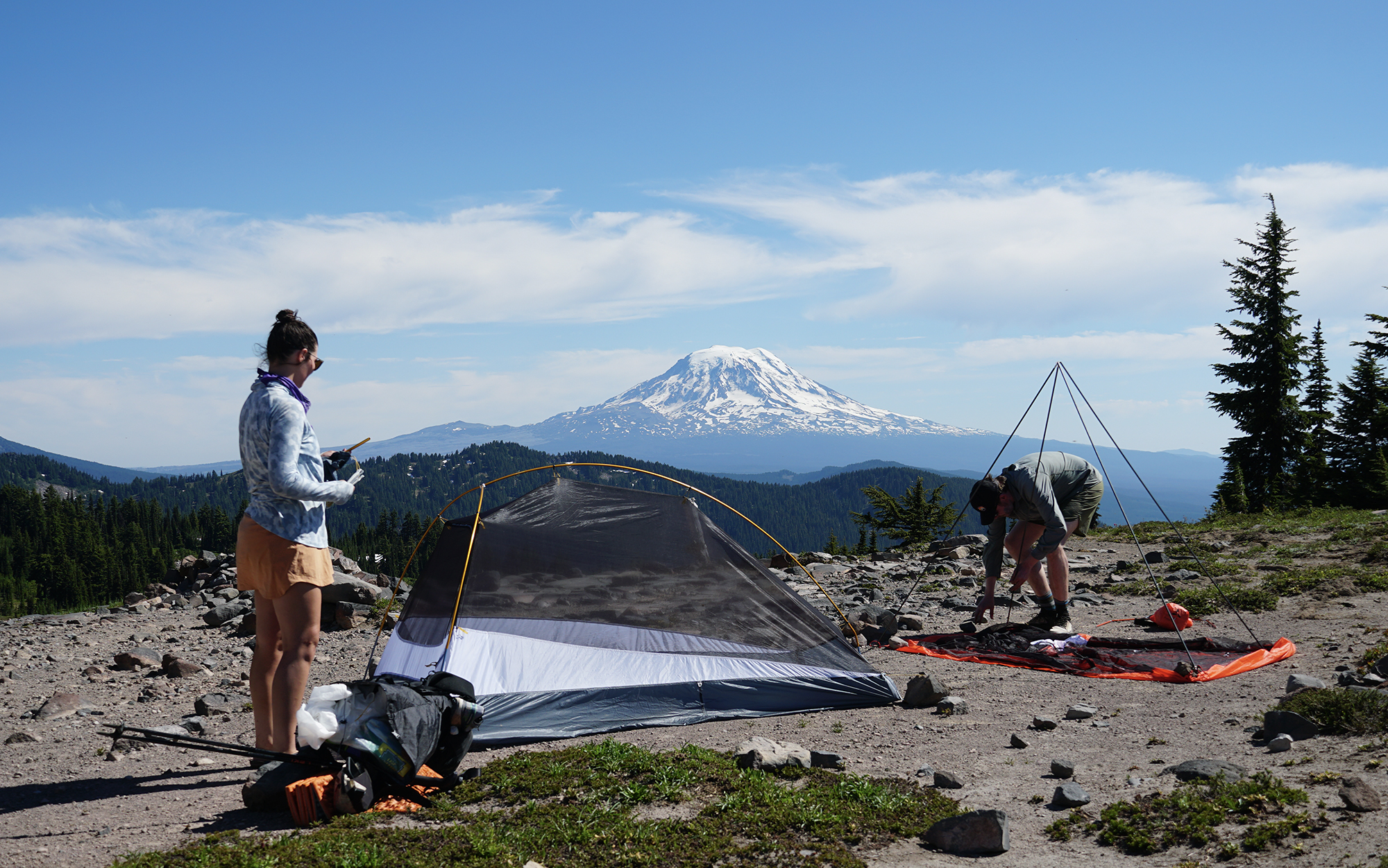 two people setting up tents in front of Mount Adams