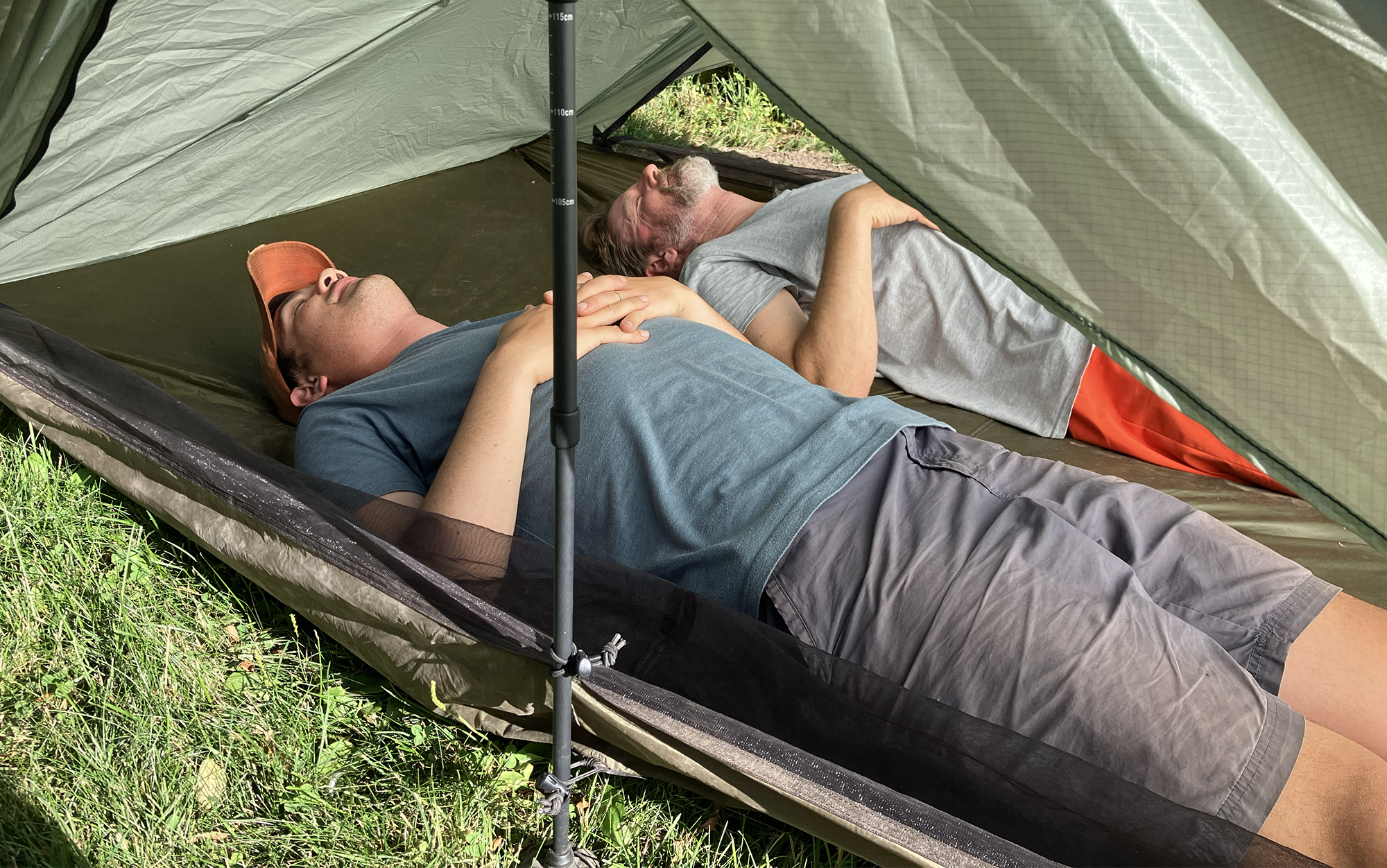 two men lying down inside of a tent