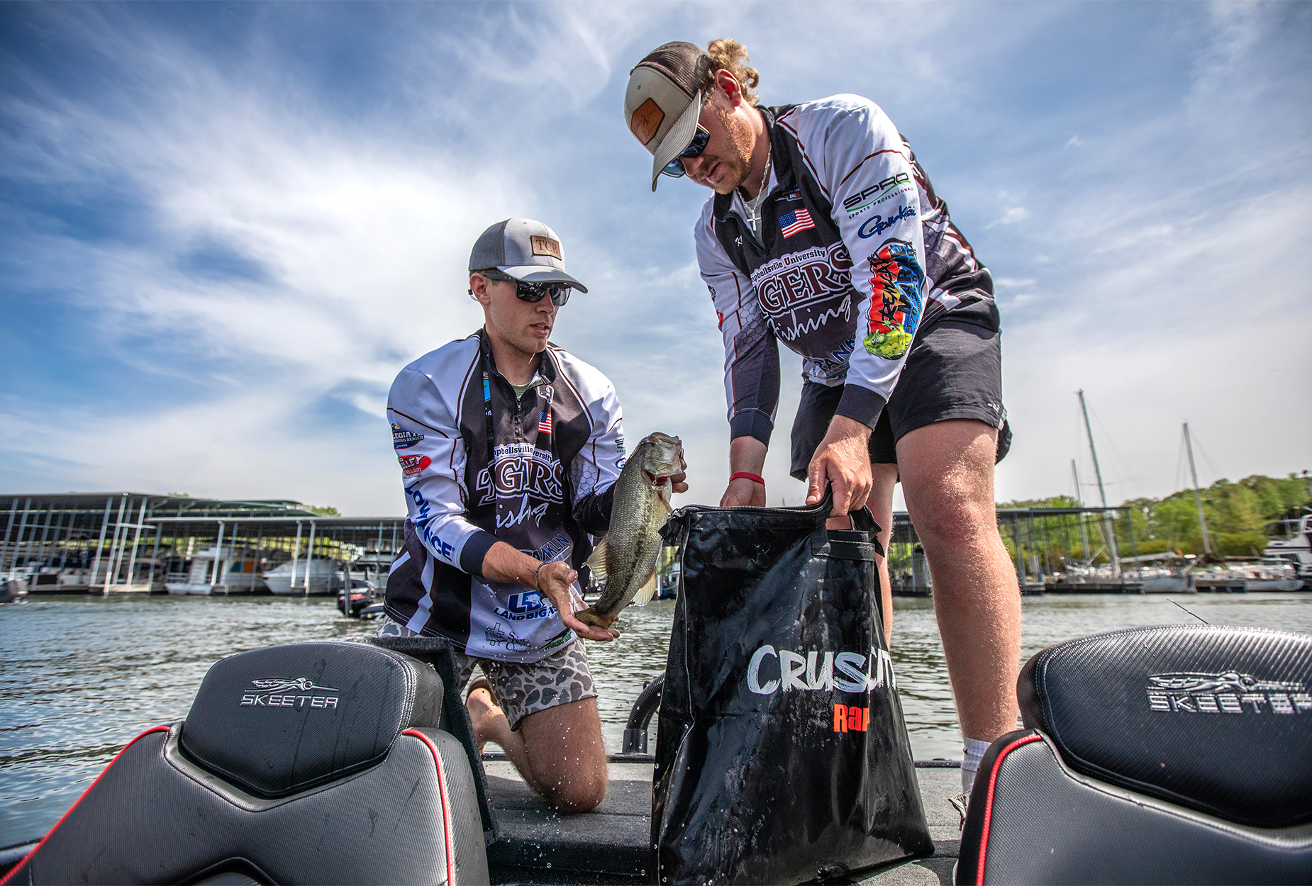 Two college anglers put a bass in a weigh bag.