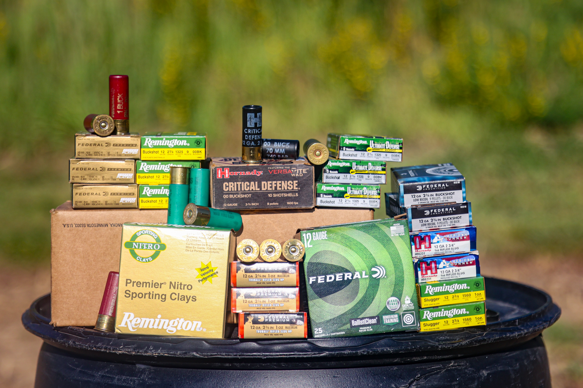 Boxes of buckshot and slugs on a black barrel at the range.